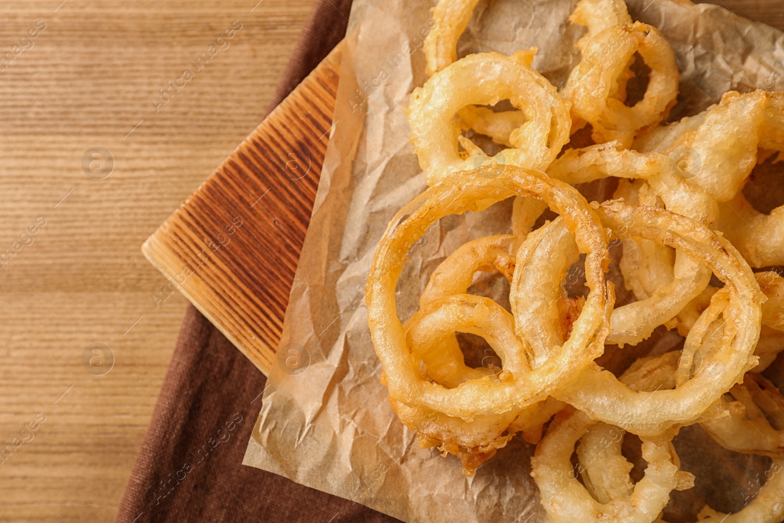 Photo of Homemade delicious golden breaded and deep fried crispy onion rings on wooden background, top view