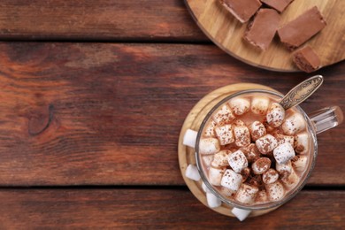 Photo of Cup of aromatic hot chocolate with marshmallows and cocoa powder on wooden table, flat lay. Space for text