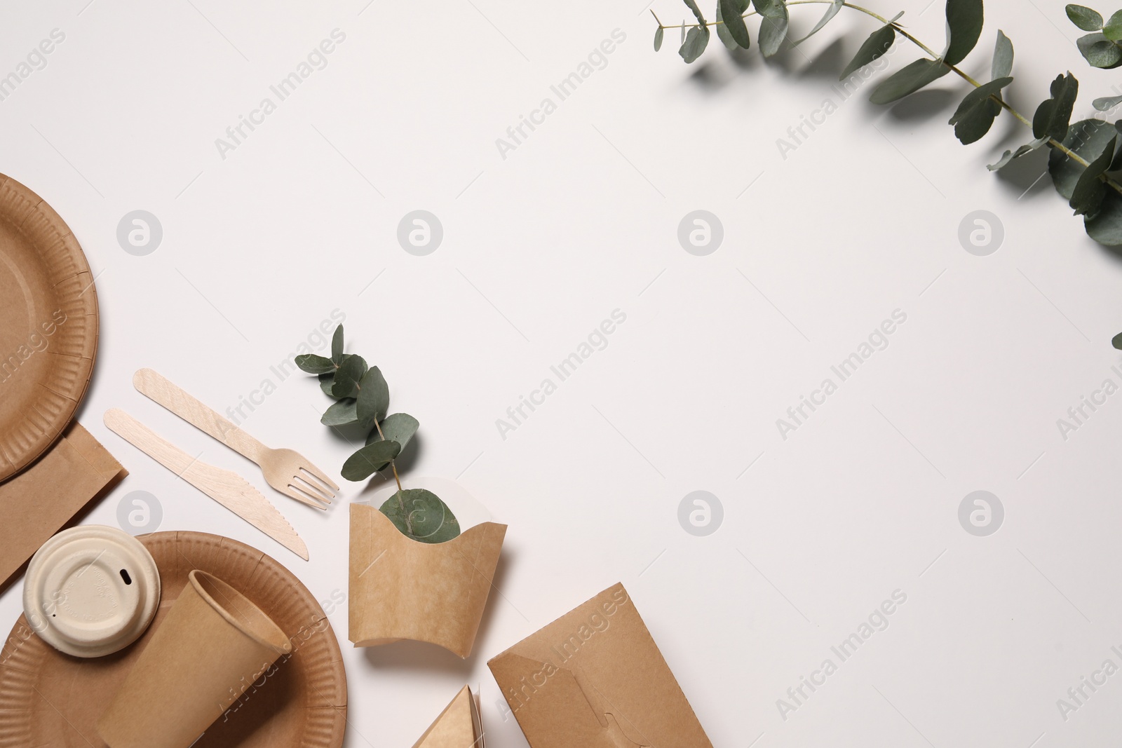 Photo of Eco friendly food packaging. Paper containers, tableware and eucalyptus branches on white background, flat lay. Space for text