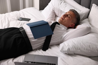 Photo of Businessman in office clothes sleeping on bed indoors