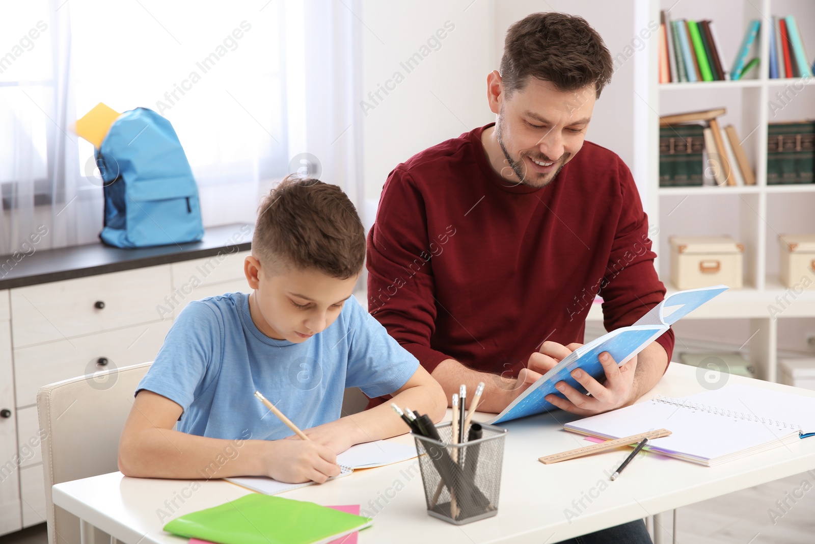 Photo of Dad helping his son with homework in room