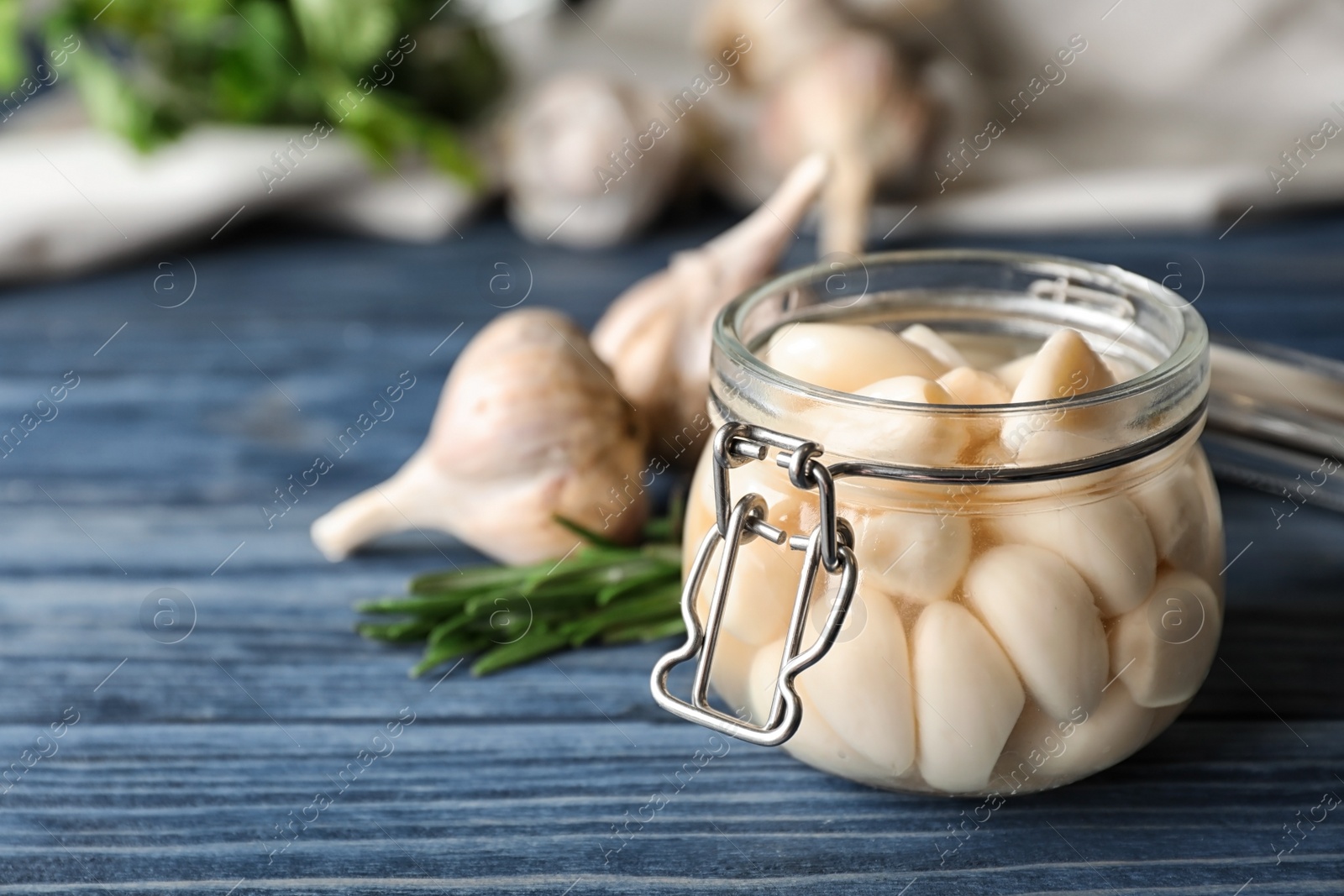 Photo of Preserved garlic in glass jar on wooden table, closeup. Space for text