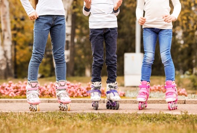 Photo of Children wearing roller skates in autumn park, focus on legs