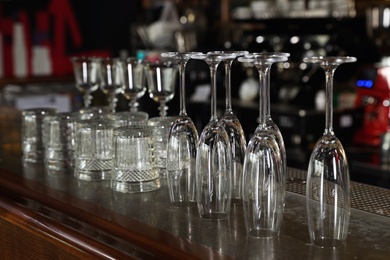 Photo of Different empty clean glasses on counter in bar