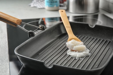 Photo of Wooden spoon with coconut oil in frying pan. Healthy cooking