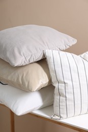 Photo of Soft pillows on table near beige wall