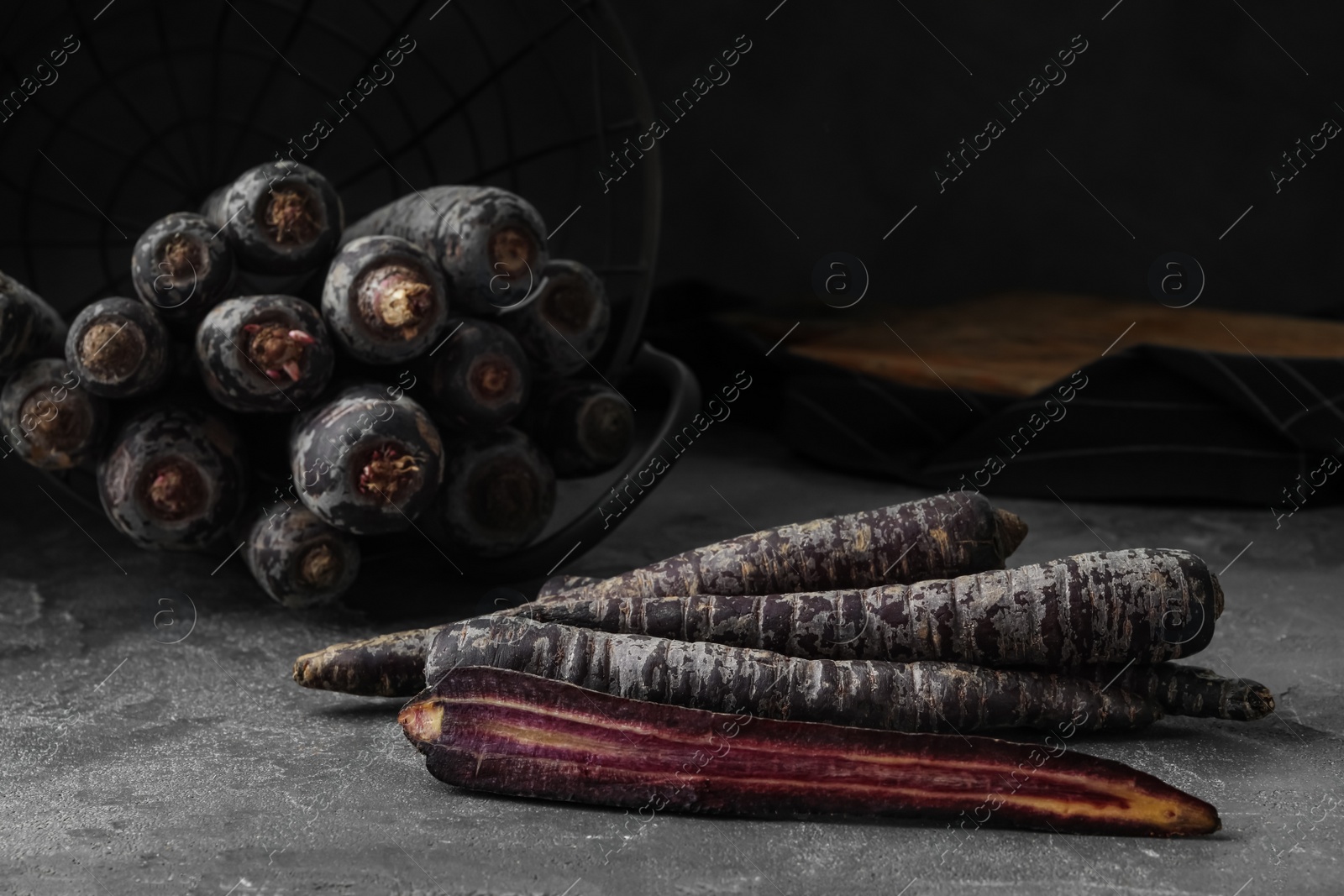 Photo of Fresh raw black carrots on grey table