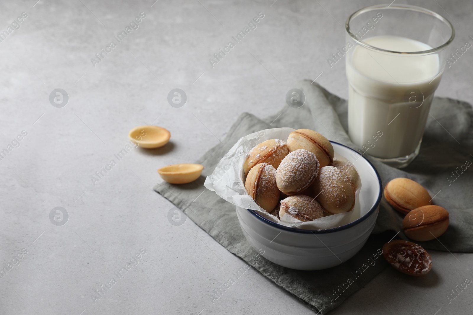 Photo of Delicious walnut shaped cookies with filling and milk on grey table. Space for text