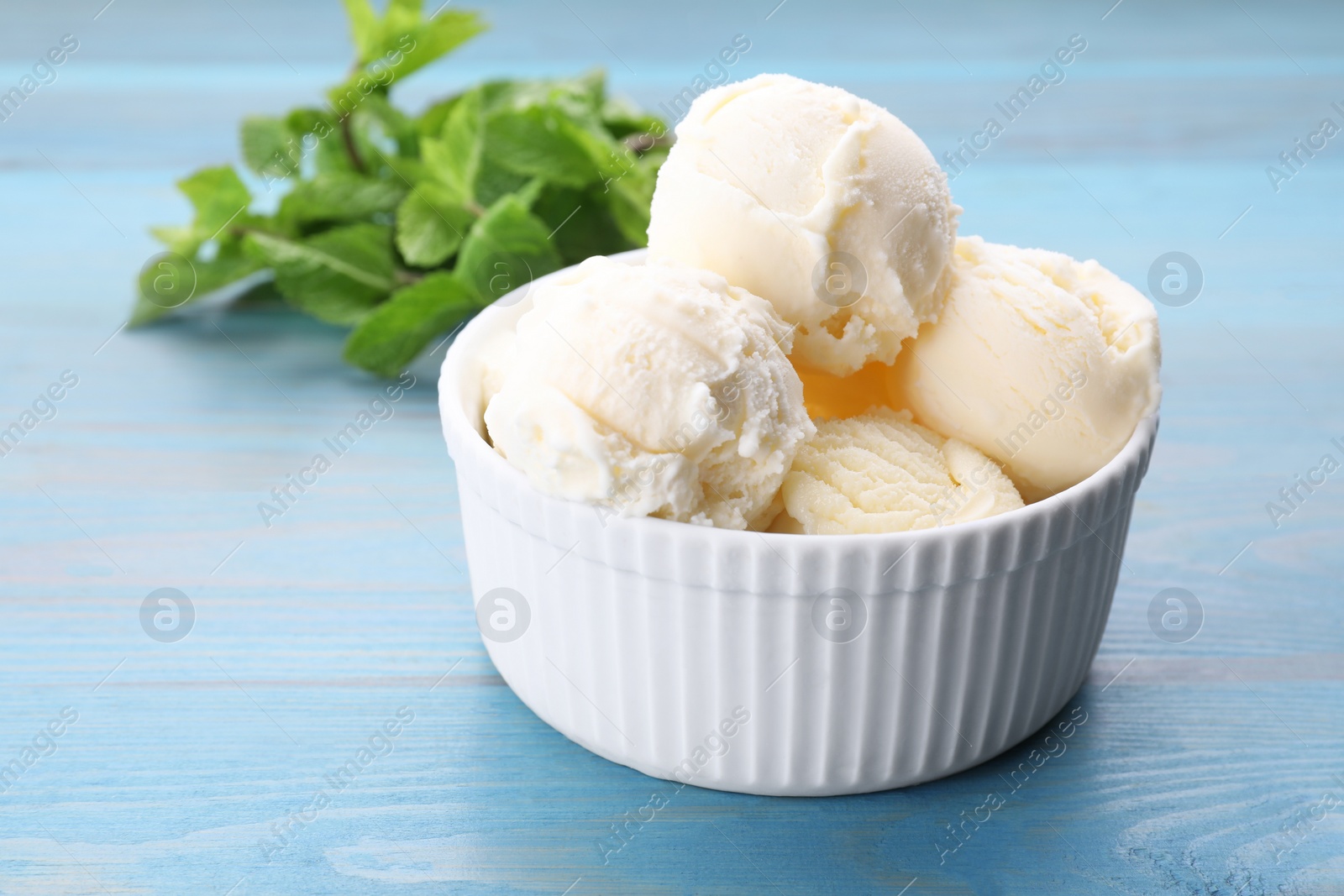 Photo of Delicious vanilla ice cream on light blue wooden table, closeup