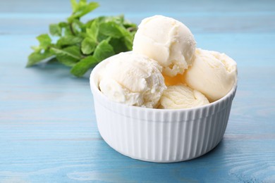 Delicious vanilla ice cream on light blue wooden table, closeup