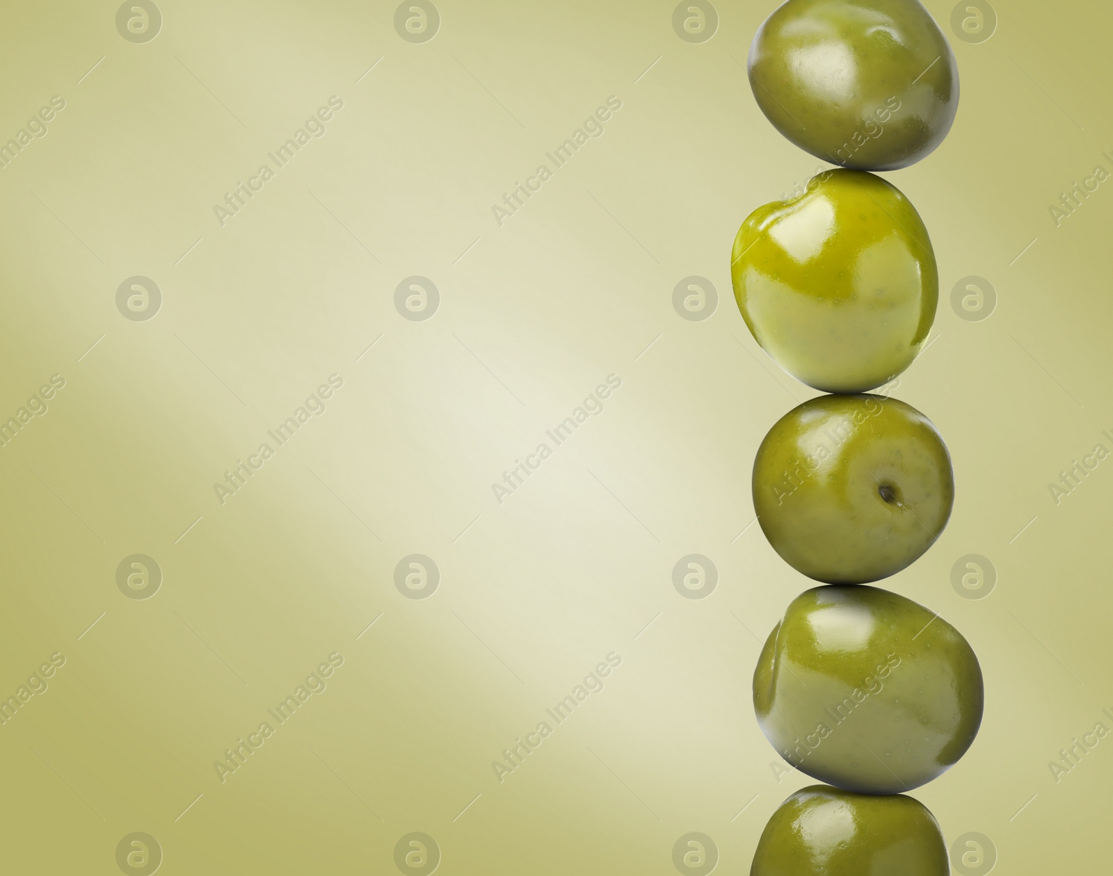 Image of Whole olives on pastel yellowish green background, space for text