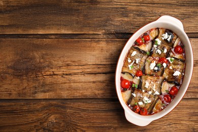 Photo of Tasty eggplant rolls with tomatoes, cheese and microgreens in baking dish on wooden table, top view. Space for text