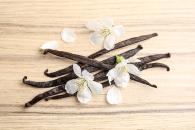 Photo of Flat lay composition with aromatic vanilla sticks and flowers on wooden background