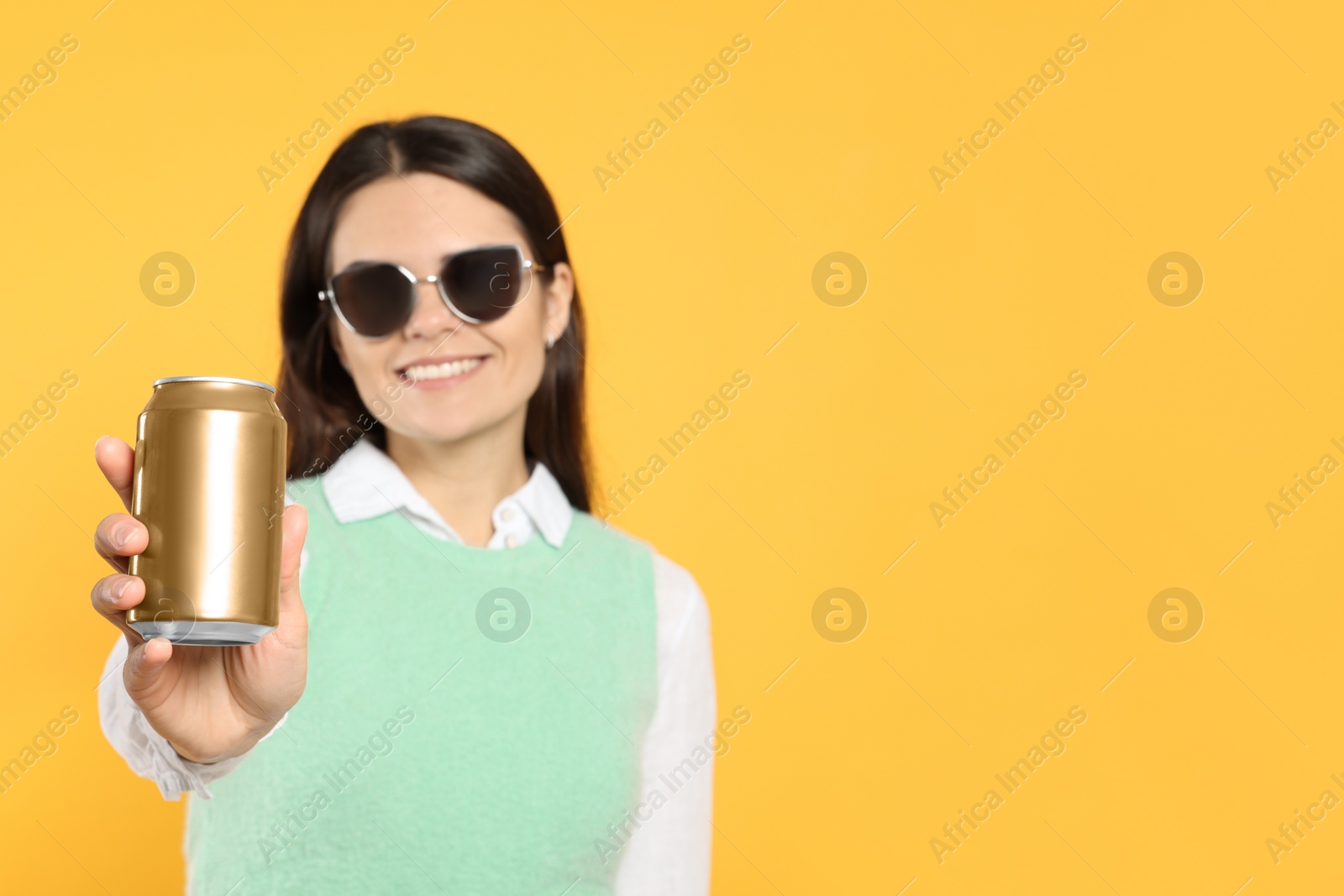 Photo of Beautiful happy woman holding beverage can on yellow background. Space for text