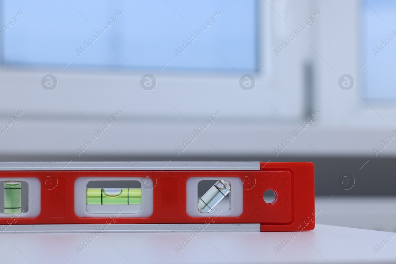 Photo of Red building level on white windowsill indoors, closeup