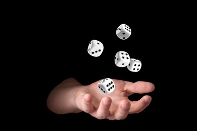 Man throwing white dice on black background, closeup