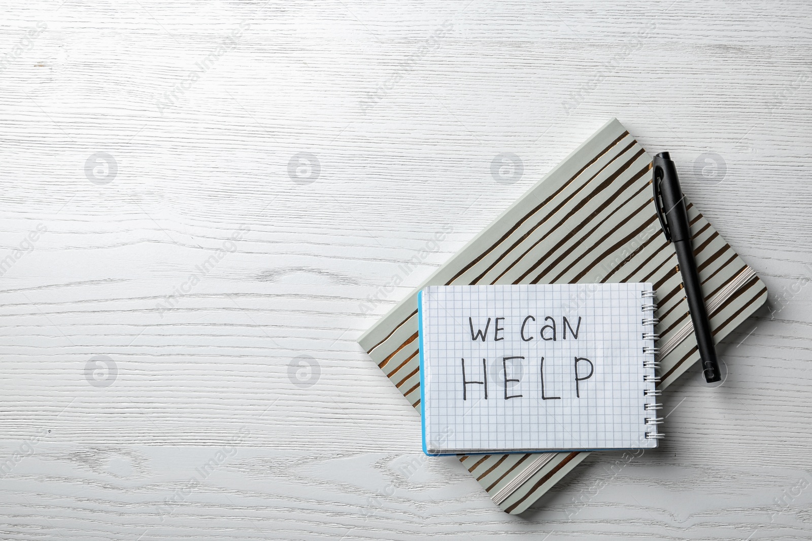 Photo of Flat lay composition with stationery, phrase WE CAN HELP and space for text on white wooden background