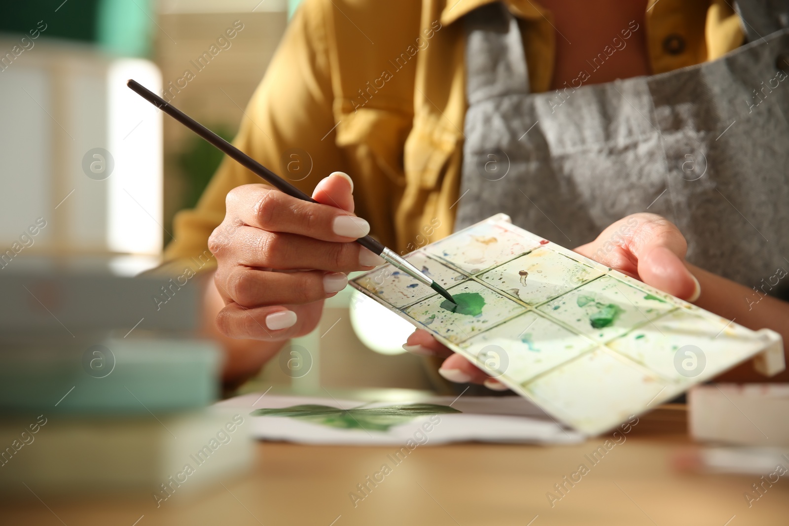 Photo of Young woman drawing leaf at table, closeup