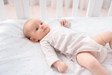 Photo of Cute little baby lying in crib at home