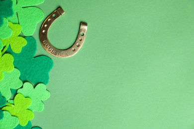 Photo of Flat lay composition with clover leaves and horseshoe on green background, space for text. St. Patrick's day