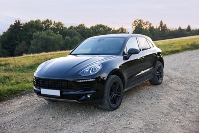 Photo of Modern black car parked on roadside outdoors