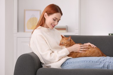 Photo of Happy woman with her cute cat on sofa at home