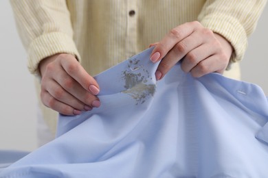 Woman holding shirt with stain against light background, closeup