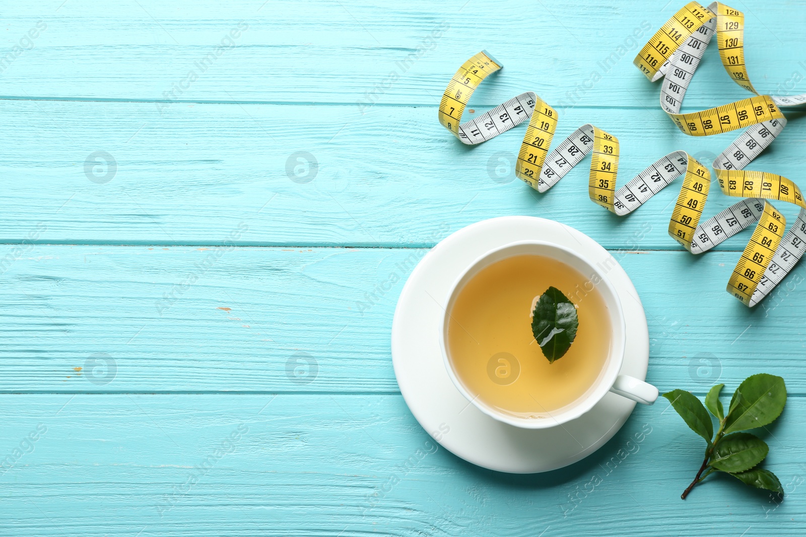 Photo of Flat lay composition with herbal diet tea and measuring tape on light blue wooden table. Space for text