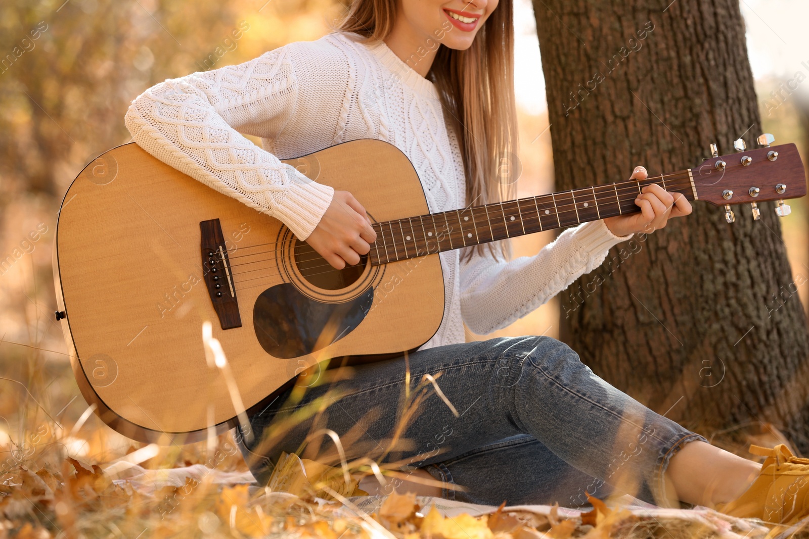 Photo of Teen girl playing guitar in autumn park, closeup