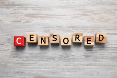 Photo of Cubes with word Censored on wooden table, flat lay