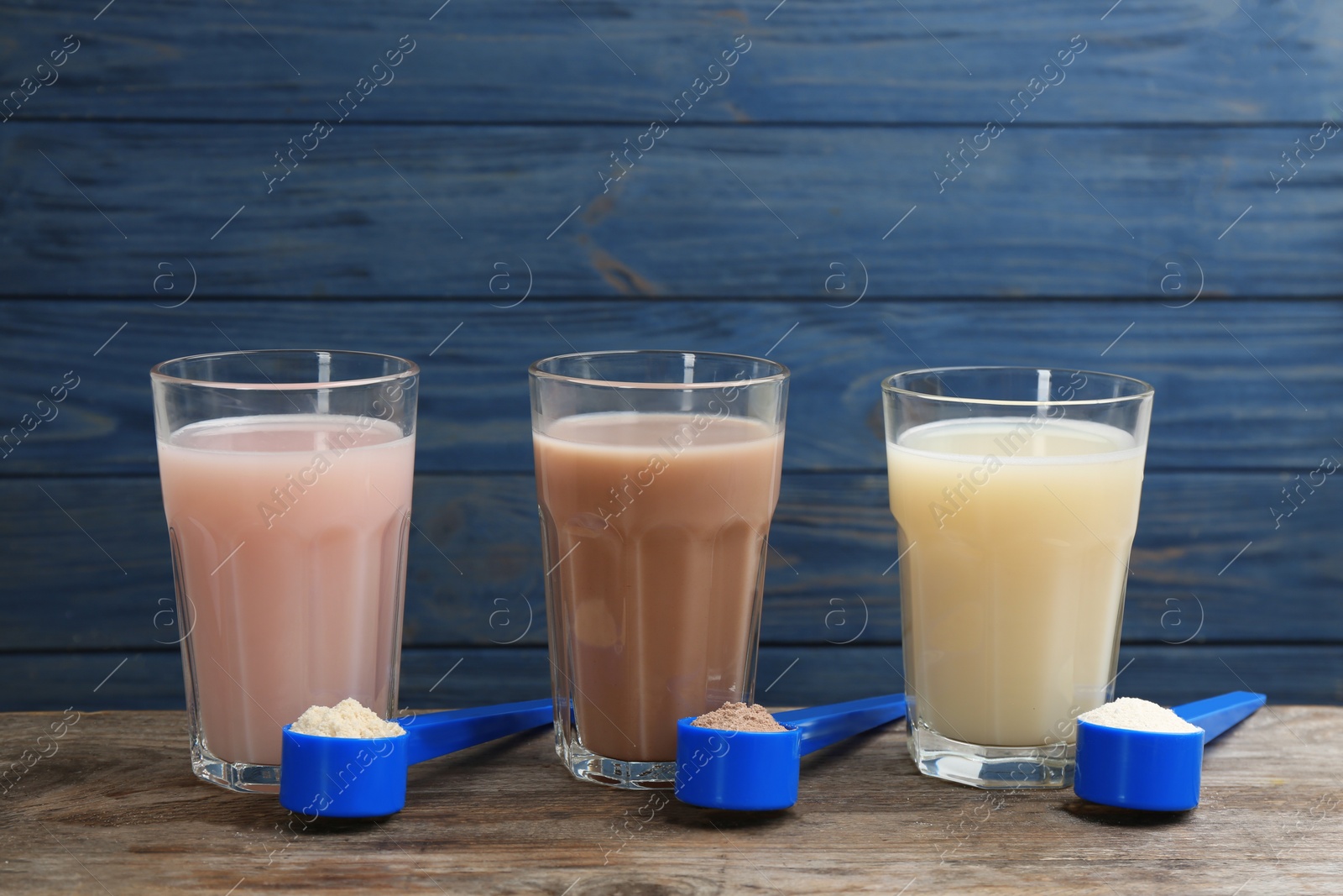Photo of Protein shakes and powder on wooden table