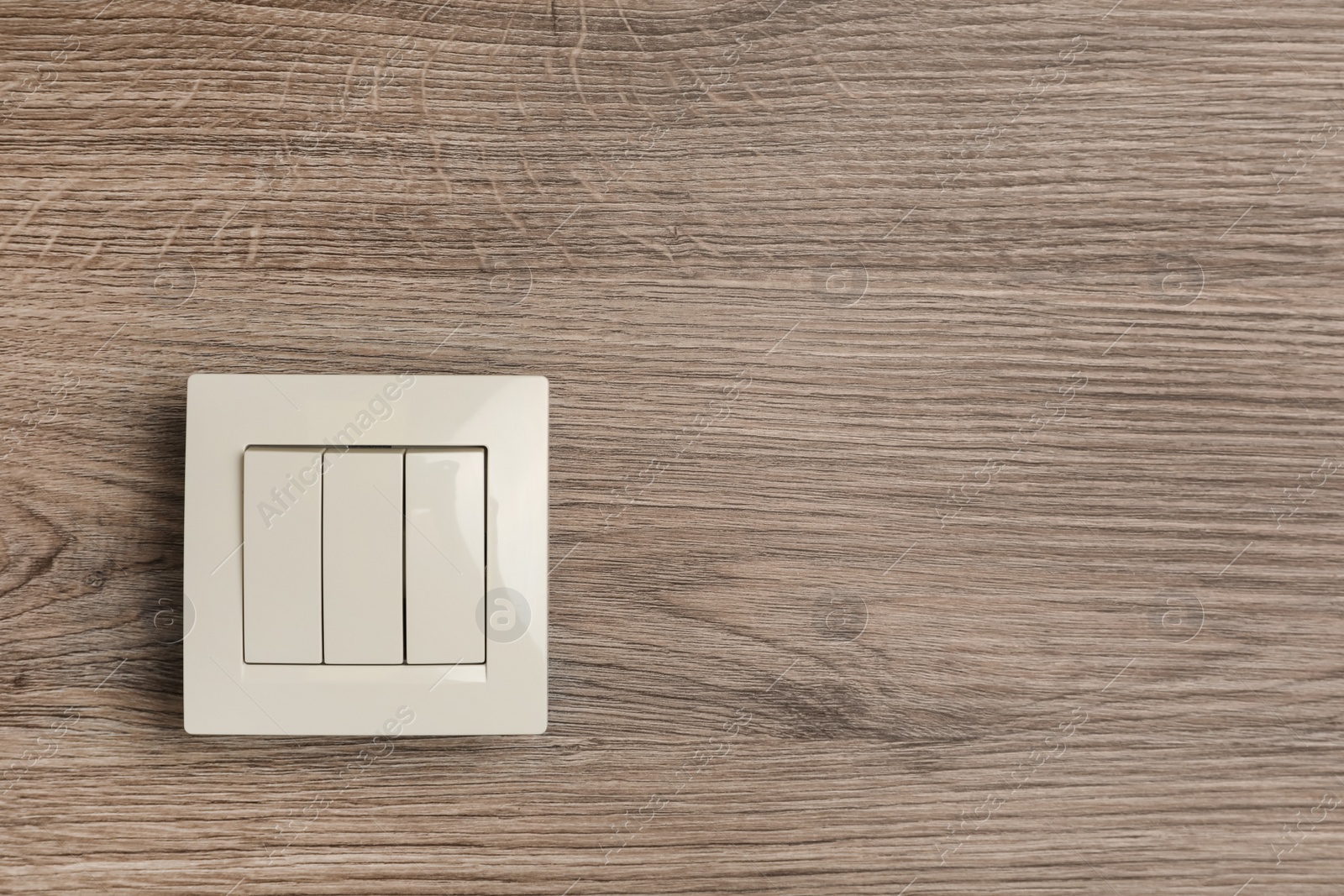 Photo of White light switch on wooden background. Space for text