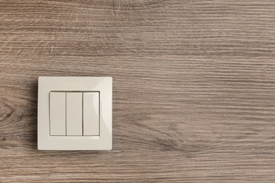 Photo of White light switch on wooden background. Space for text