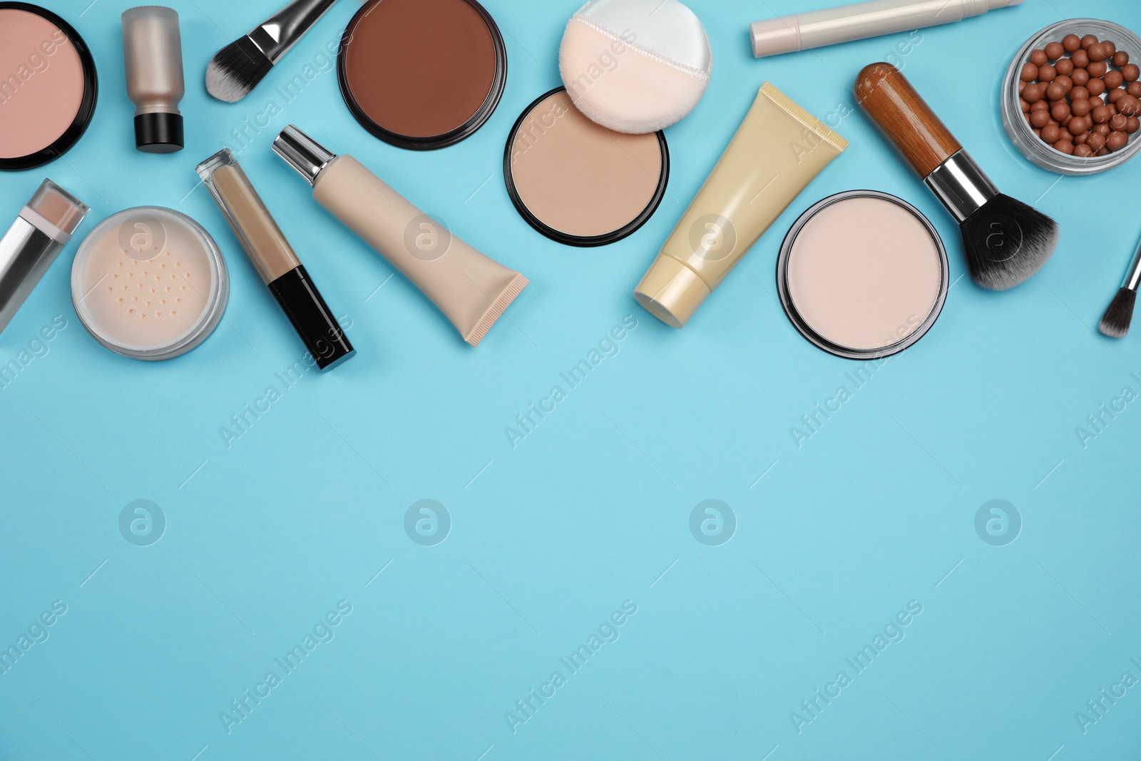 Photo of Face powders and other decorative cosmetic products on light blue background, flat lay. Space for text