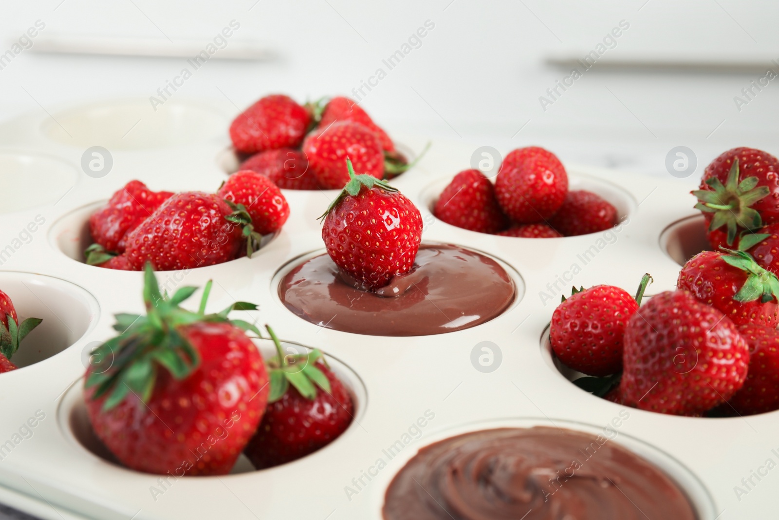 Photo of Mold with melted chocolate and ripe strawberries, closeup