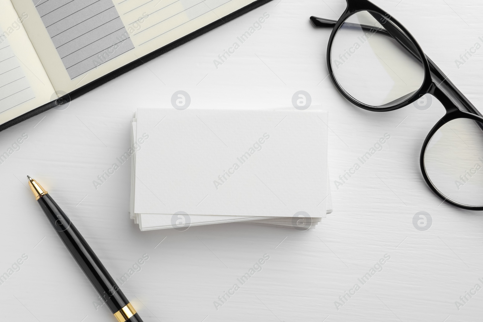 Photo of Blank business cards, glasses, notebook and pen on white table, flat lay. Mockup for design