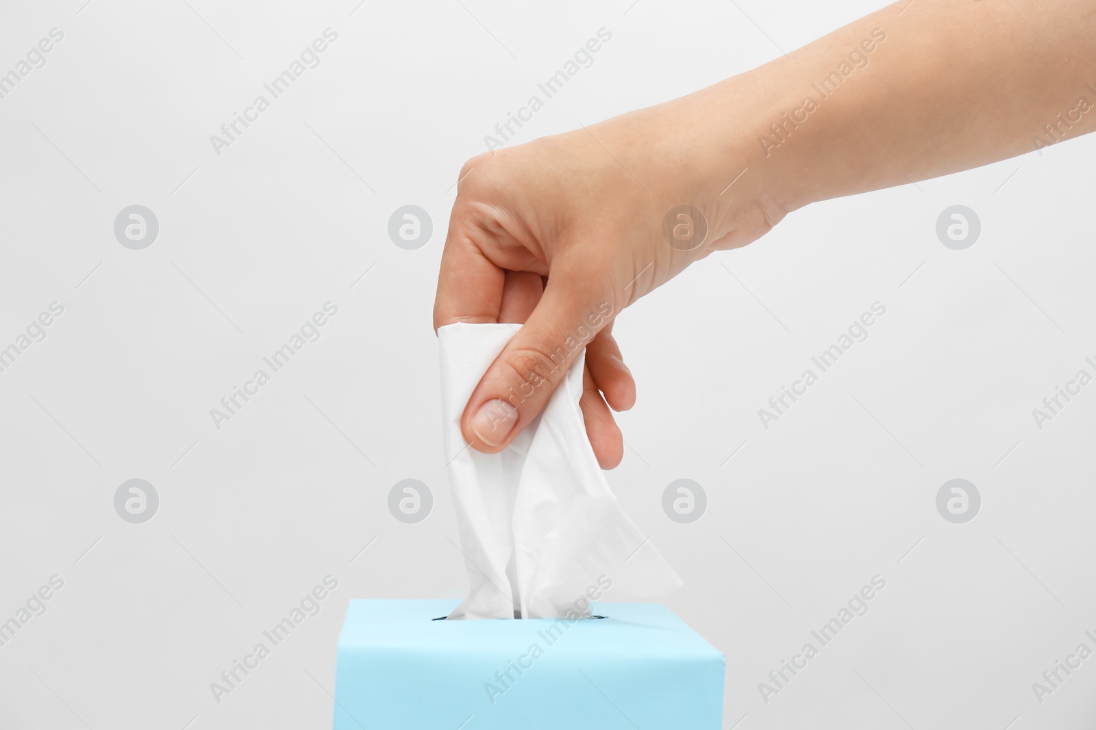 Photo of Woman taking paper tissue from box on light background, closeup