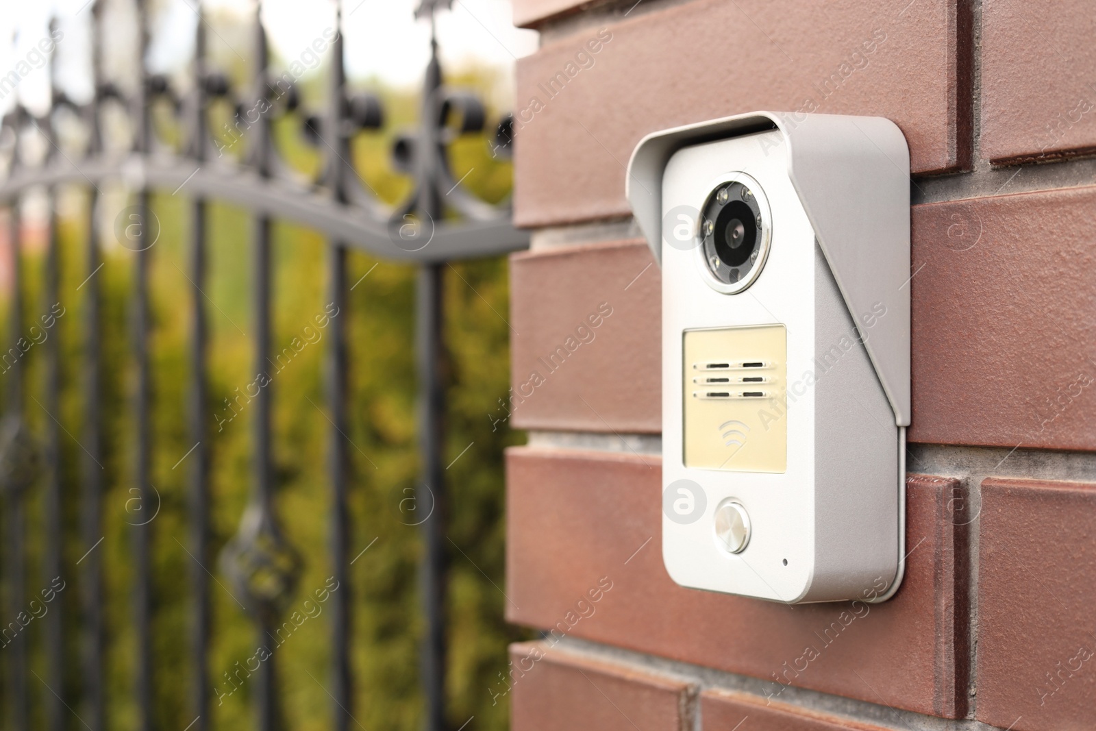 Photo of Modern intercom on red wall near gates outdoors, space for text