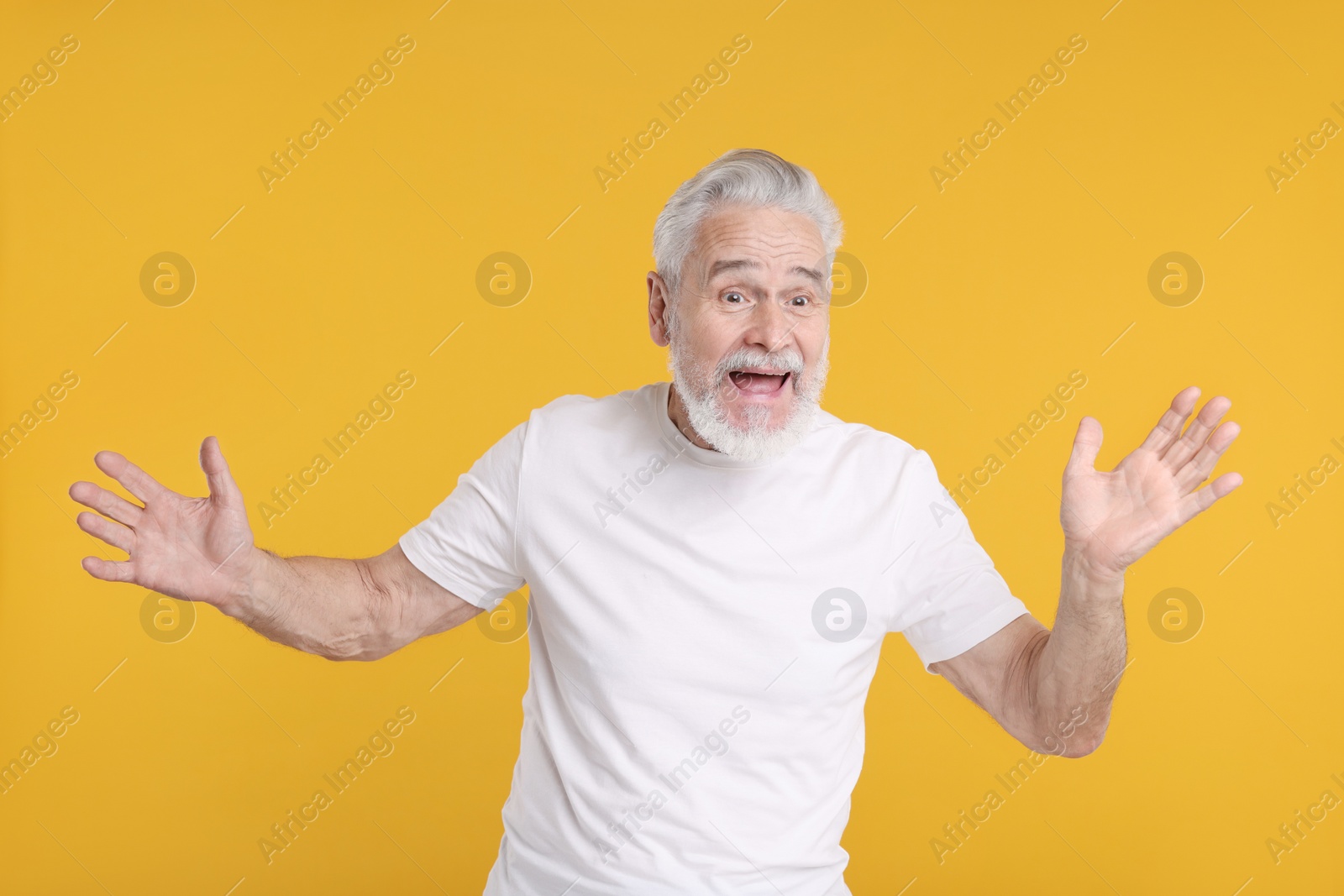 Photo of Portrait of surprised senior man on yellow background