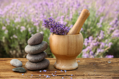 Photo of Spa stones, fresh lavender flowers and mortar on wooden table outdoors, closeup
