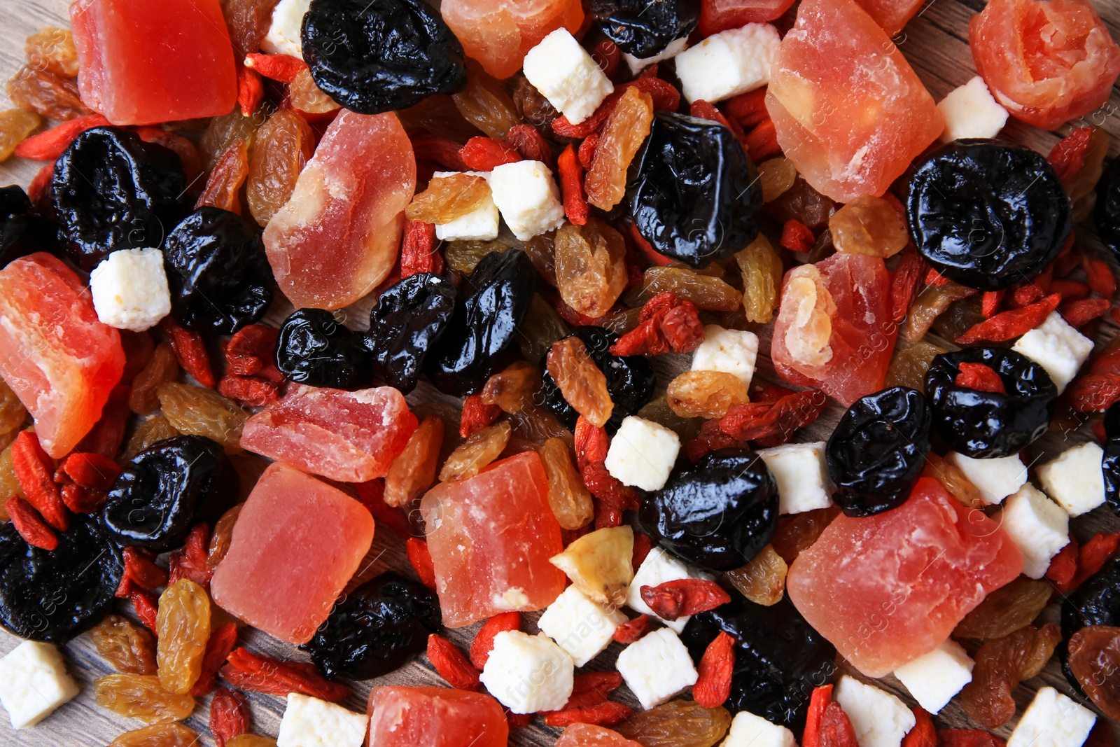 Photo of Pile of different tasty dried fruits on wooden table, flat lay