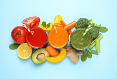 Delicious juices and fresh ingredients on light blue background, flat lay