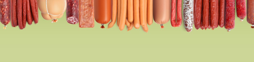 Image of Many different tasty sausages on light green background, flat lay. Banner design