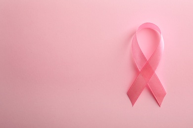 Photo of Pink ribbon on color background, top view with space for text. Breast cancer awareness concept