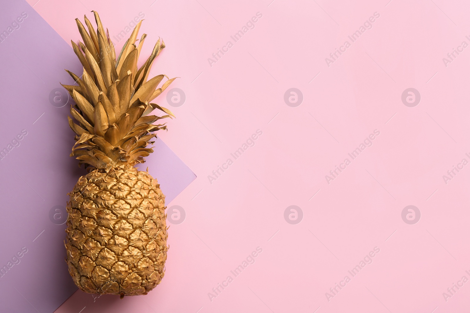 Photo of Golden pineapple on color background, top view with space for text. Creative concept