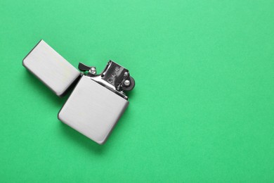 Photo of Gray metallic cigarette lighter on green background, top view. Space for text