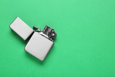 Gray metallic cigarette lighter on green background, top view. Space for text