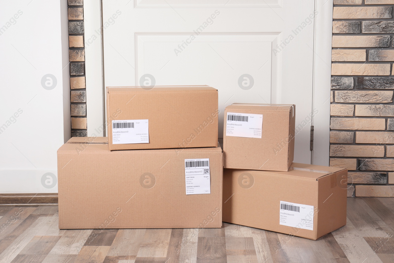 Photo of Cardboard parcel boxes on floor near apartment entrance. Mockup for design