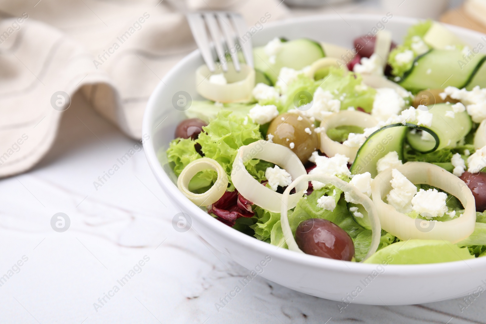 Photo of Bowl of tasty salad with leek, olives and cheese on white marble table, closeup. Space for text
