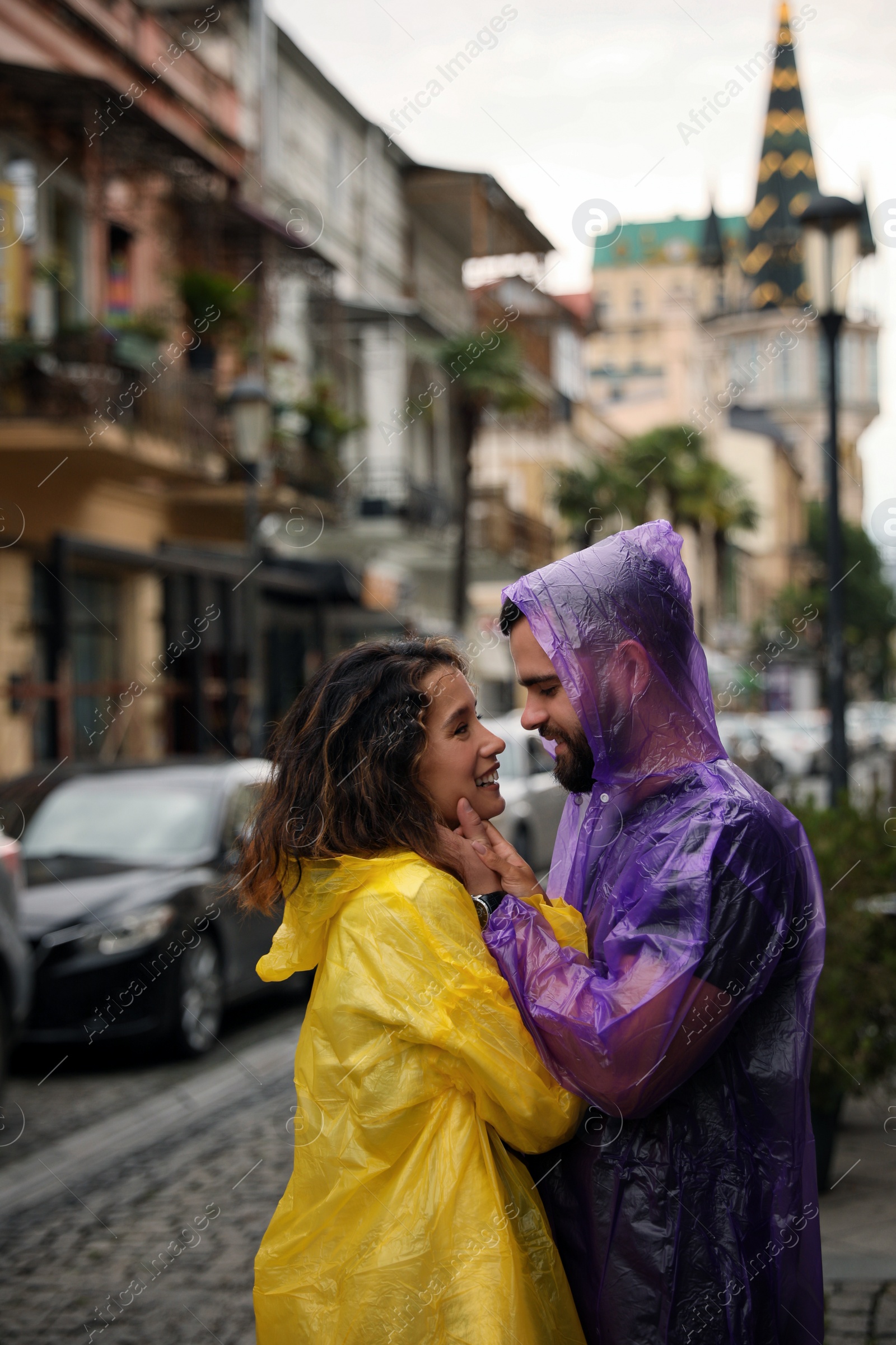 Photo of Young couple in raincoats enjoying time together on city street